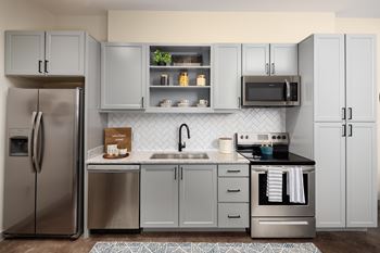 A modern kitchen with a refrigerator, microwave, oven, and sink.